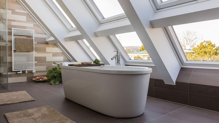 Bagno moderno con vasca da bagno freestanding collocata davanti a diverse finestre che arrivano fino al pavimento