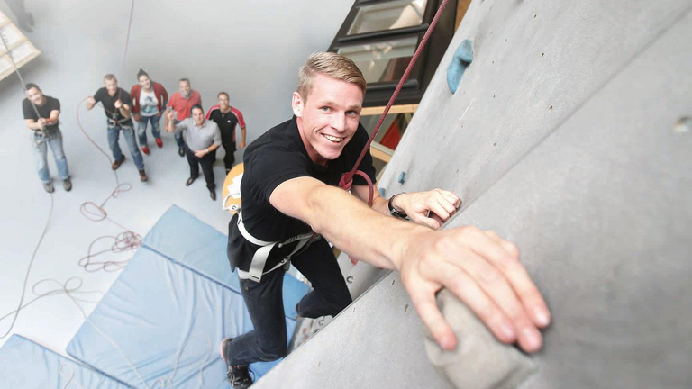 Ein junger Mann klettert eine Kletterwand hoch